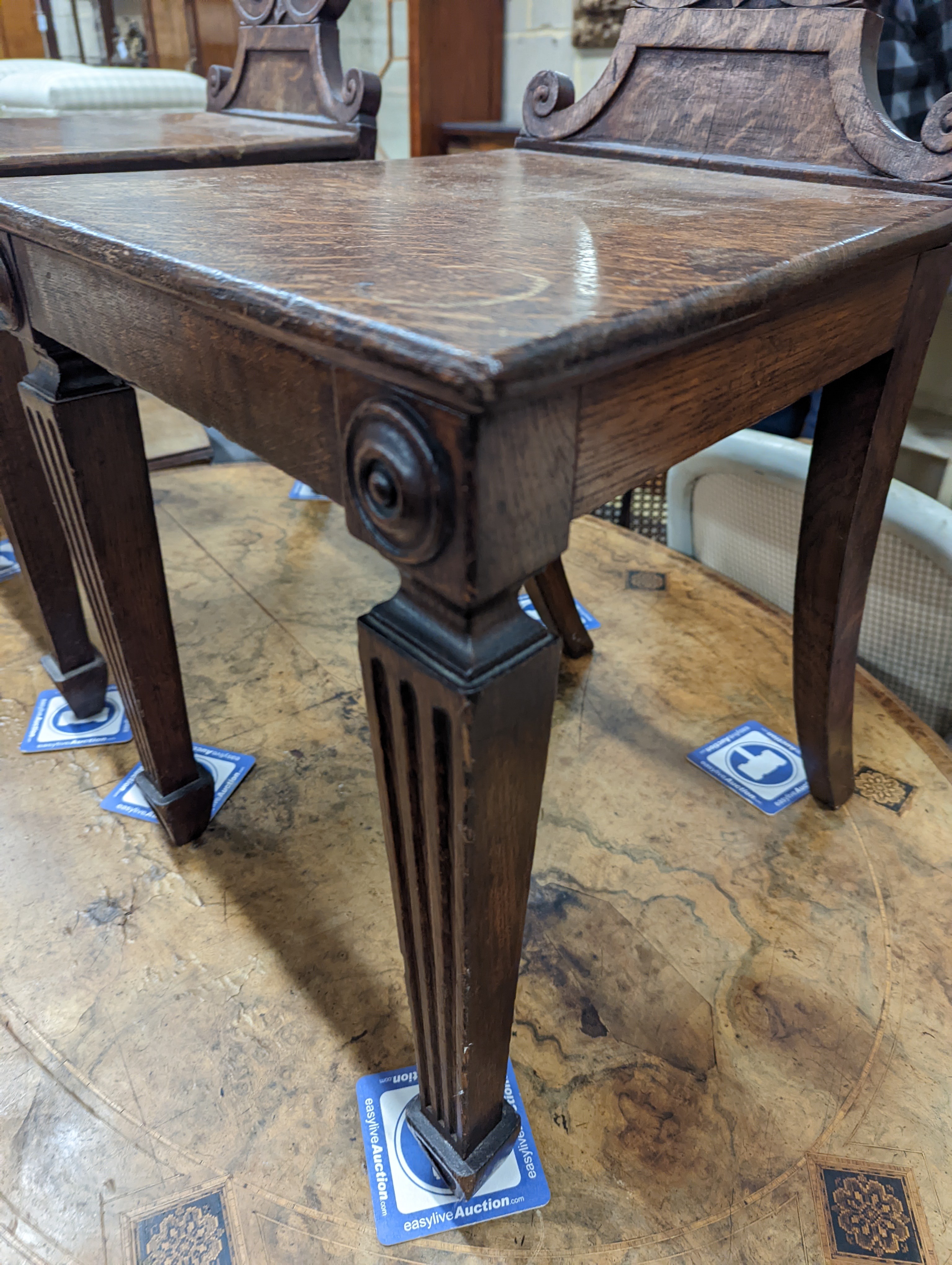 A pair of Victorian oak hall chairs with painted armorials, width 43cm, depth 39cm, height 94cm